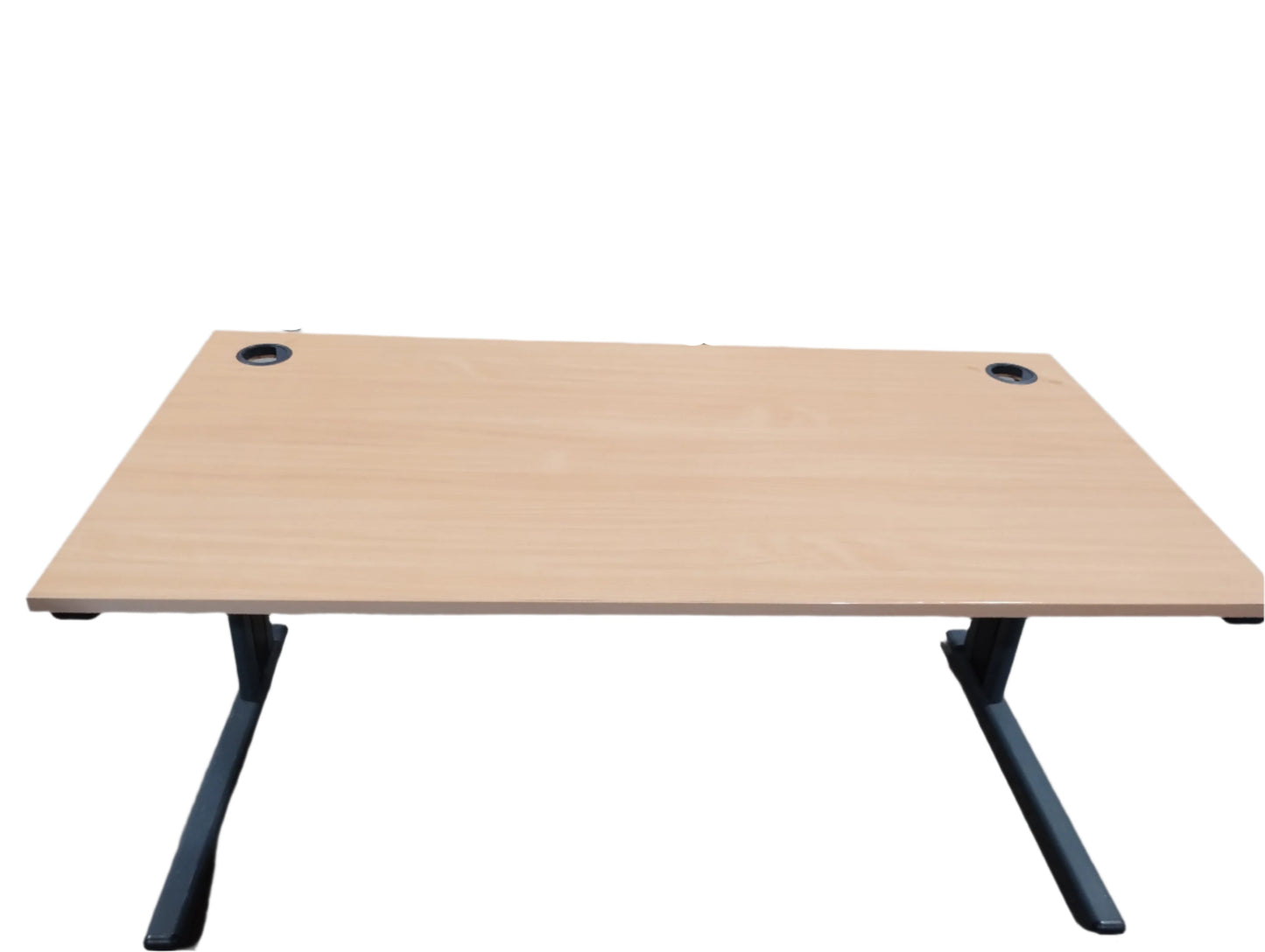 Wooden desk with black legs on a concrete floor