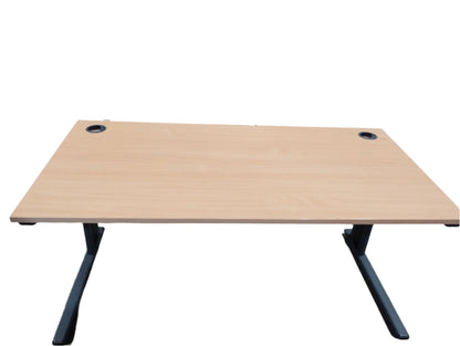 Wooden desk with black legs on a concrete floor